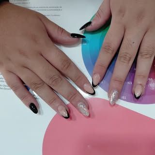 Manos con uñas almendradas, algunas negras, otras con puntas negras, una con brillo. Descansando sobre un círculo cromático.