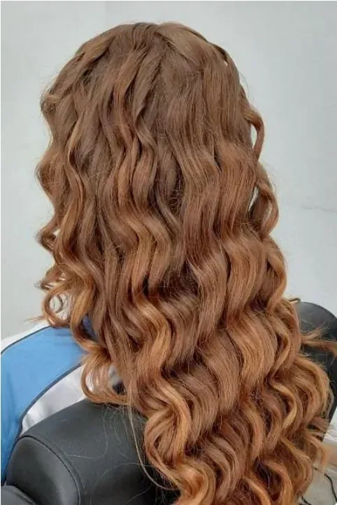Mujer con cabello castaño rojizo largo y ondulado. Una trenza recorre la parte superior.