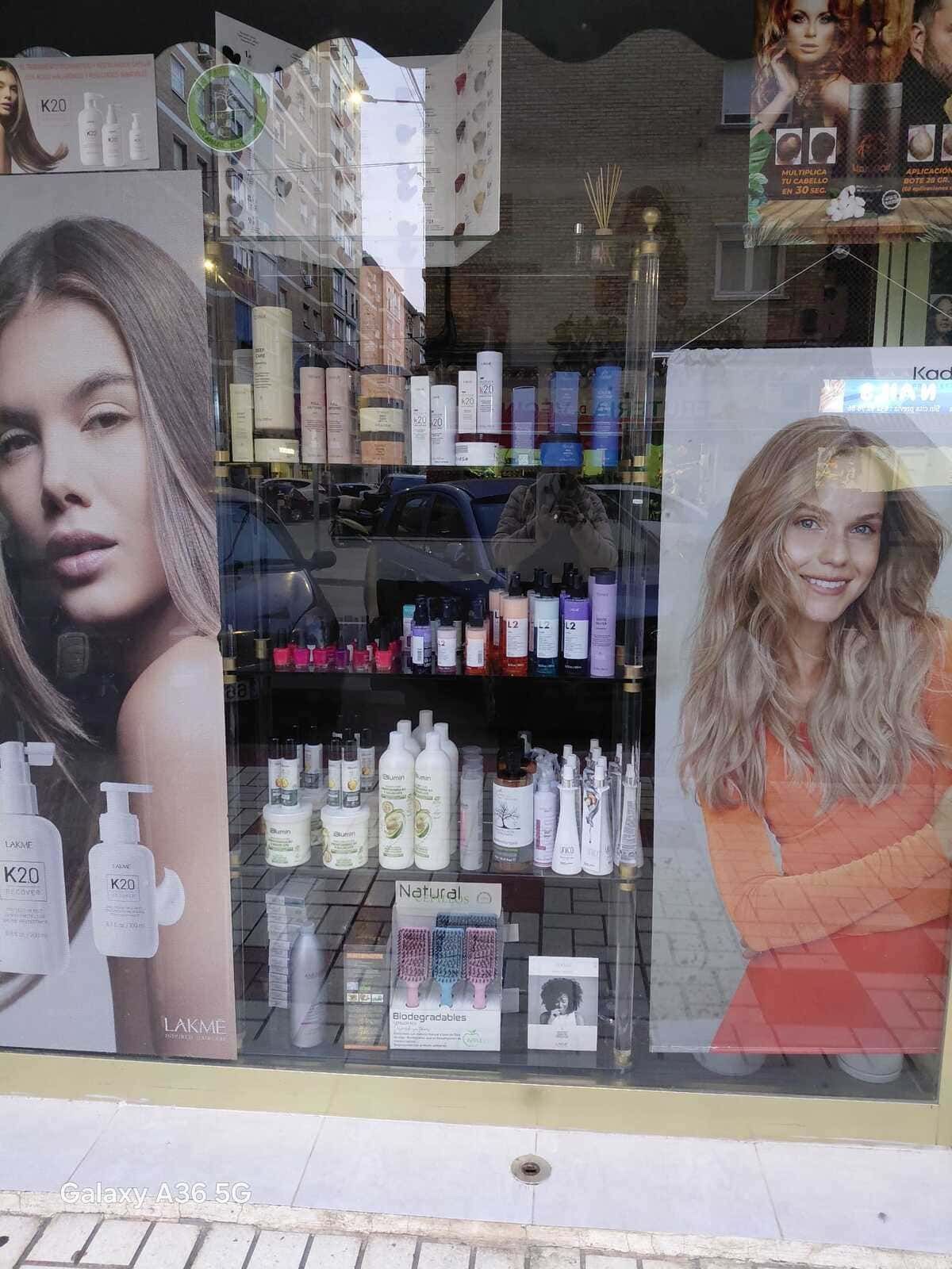 Escaparate de peluquería con exposición de productos y carteles de mujeres.