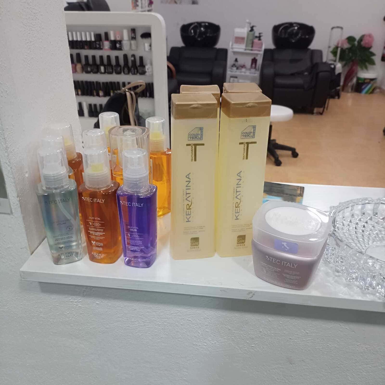 Productos capilares expuestos en un estante de un salón de belleza. Incluye botellas de spray, cajas de champú y un envase de crema.