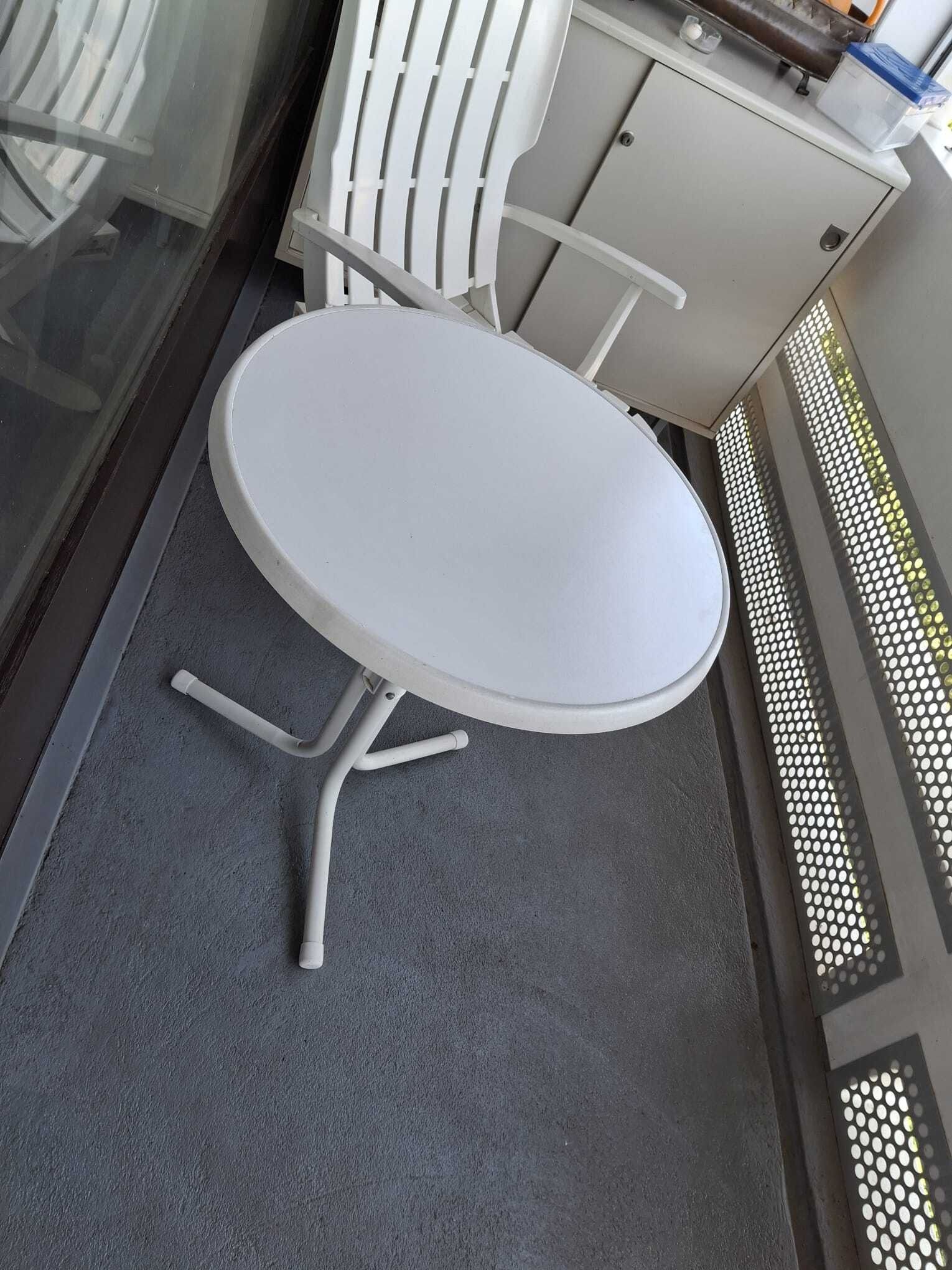 Petite table ronde blanche et chaise sur un balcon au sol et à la rambarde gris.