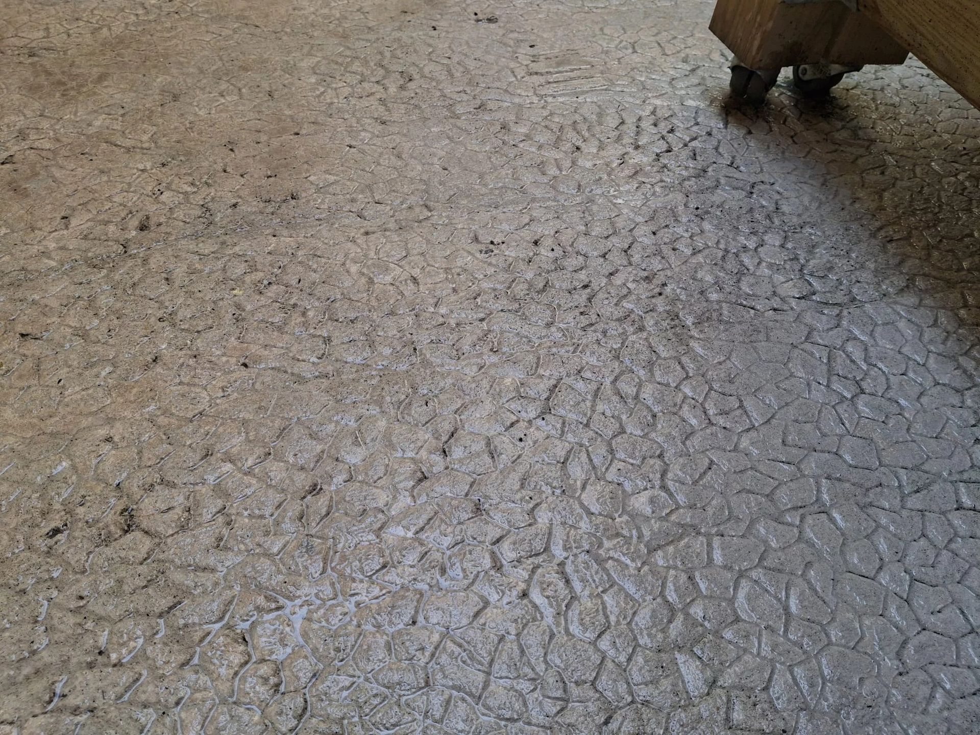 Sol en béton fissuré avec un objet sombre projetant une ombre dans le coin supérieur droit
