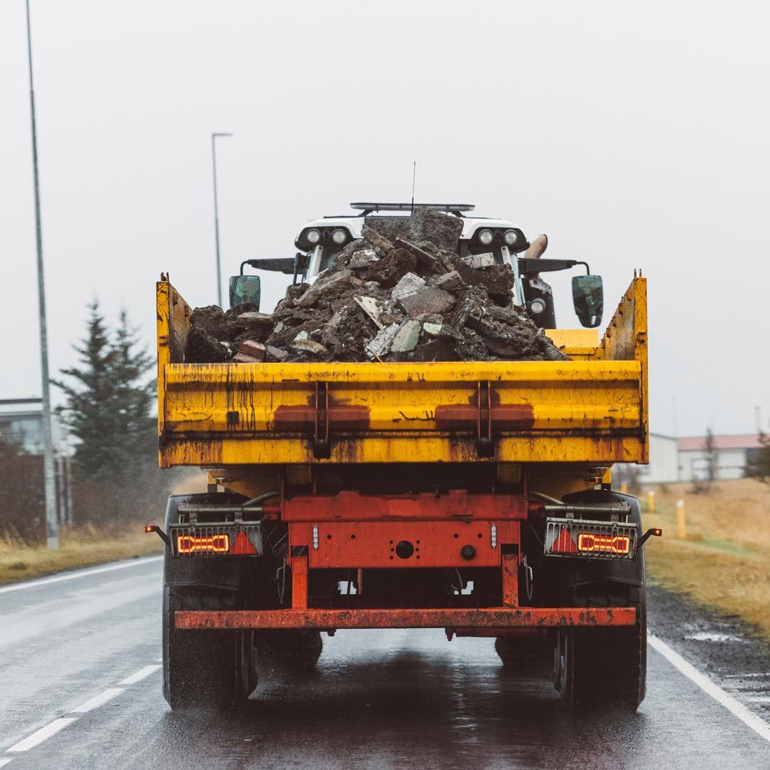Un camión volquete amarillo circula por una carretera mojada
