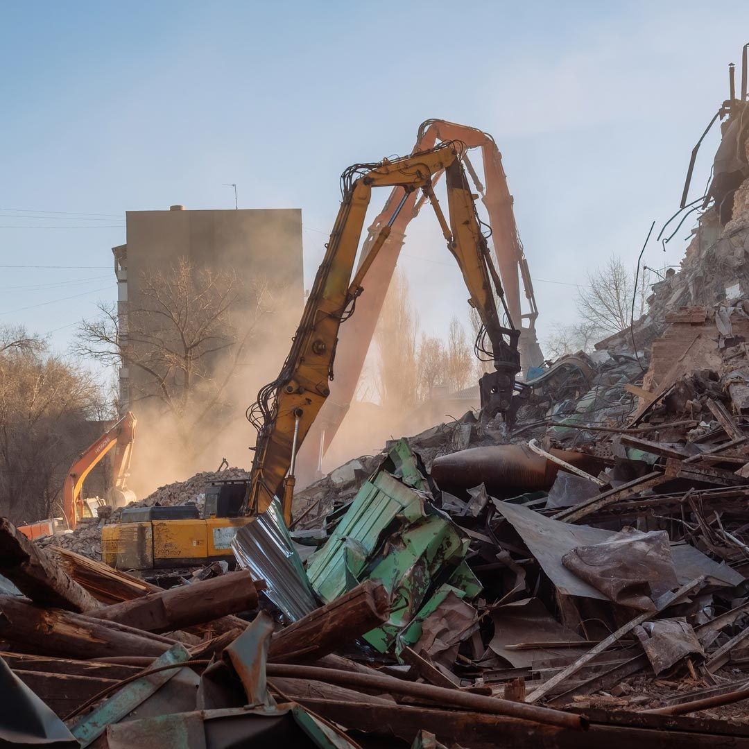 Una gran garra de metal se encuentra frente a una pila de chatarra.