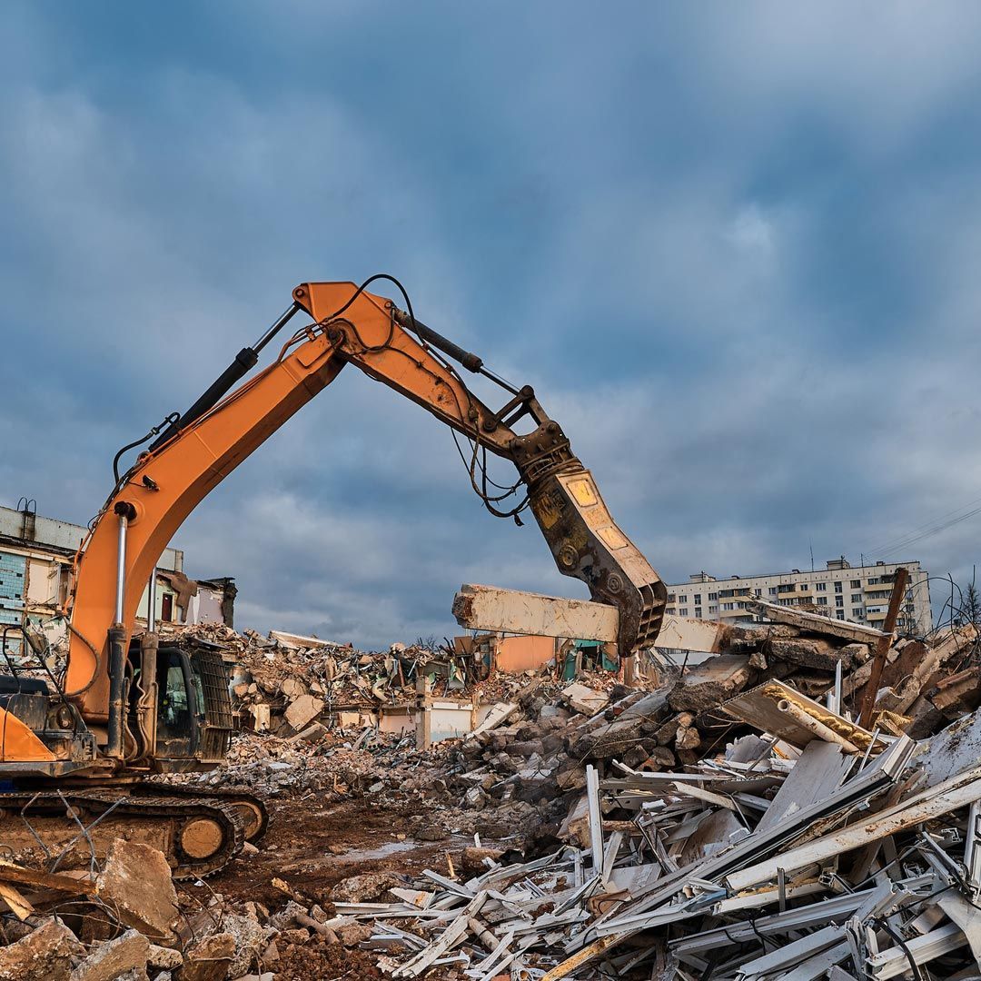 Una excavadora está demoliendo un edificio en una pila de escombros.