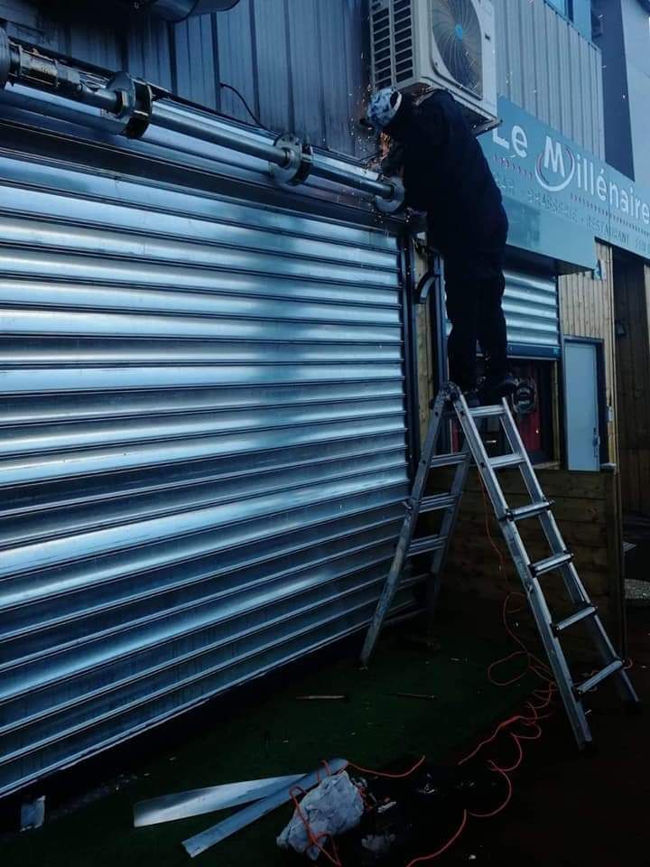 Un serrurier qui pose un rideau métallique