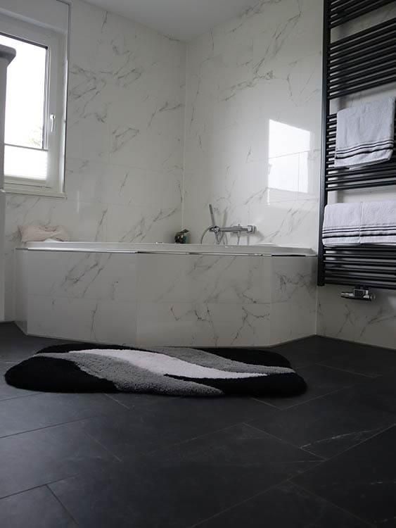 Ein Badezimmer mit Badewanne und einem Teppich auf dem Boden.