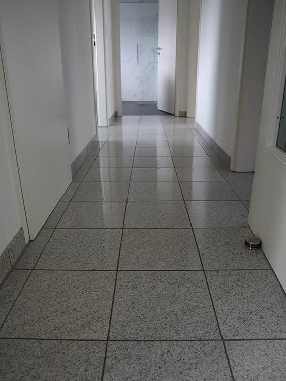 Ein langer Flur mit gefliestem Boden und einer Tür.