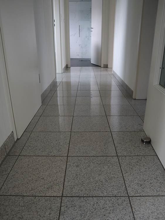Ein langer Flur mit gefliestem Boden und einer Tür.