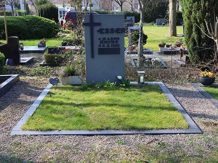 Ein Grab auf einem Friedhof mit einem Kreuz darauf