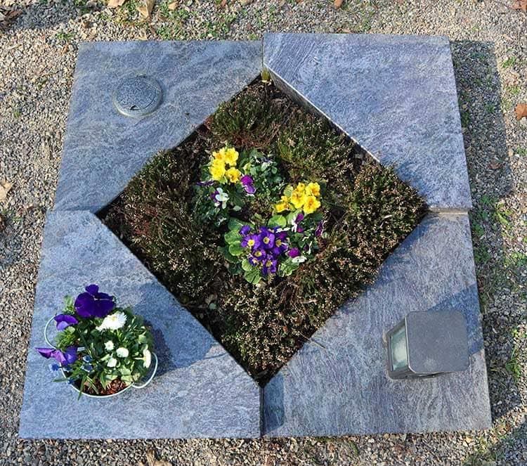 Ein Grab mit Blumen und einer Kerze darin