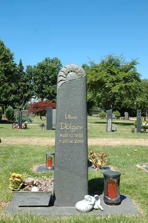 Ein Grabstein auf einem Friedhof mit einer Sonne darauf