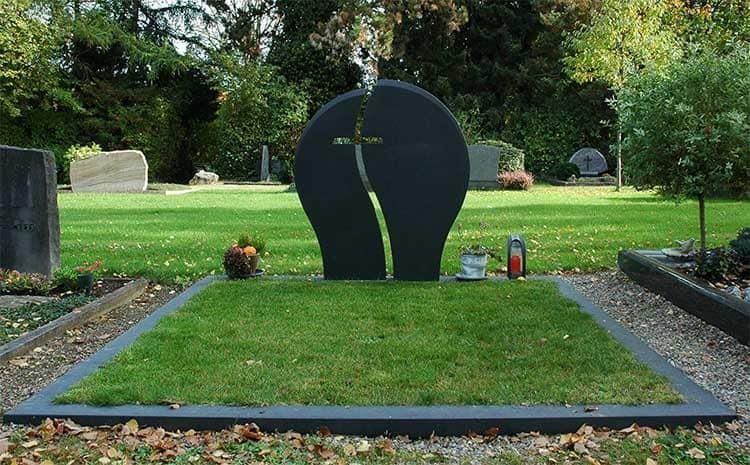 Ein Grab auf einem Friedhof mit einem Kreuz darauf