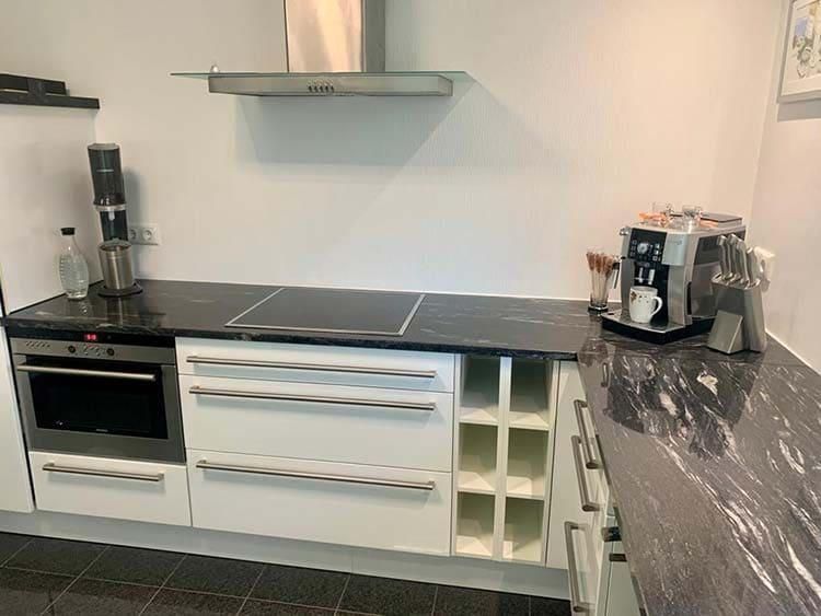 Eine Küche mit weißen Schränken, einem Herd mit Backofen und einer Kaffeemaschine.