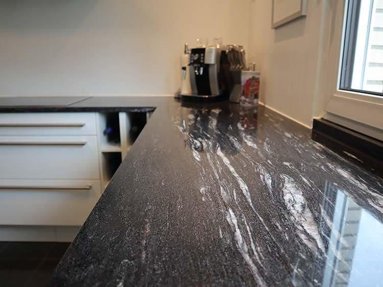 Eine Küche mit schwarzer Granitarbeitsplatte und weißen Schränken