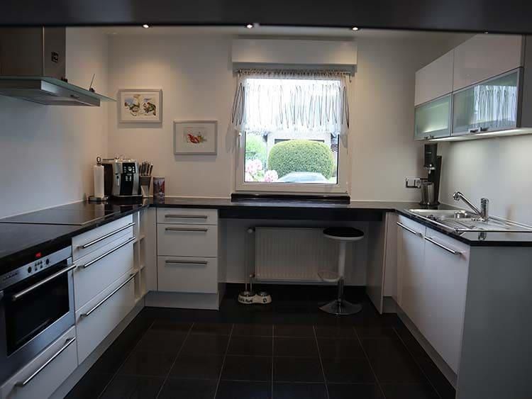 Eine Küche mit weißen Schränken und schwarzen Arbeitsplatten