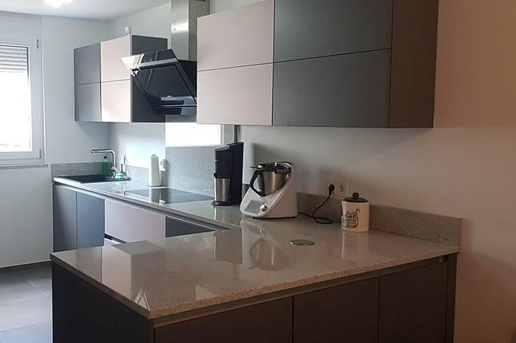 Eine Küche mit Herd, Backofen, Mikrowelle und Mixer auf der Anrichte.