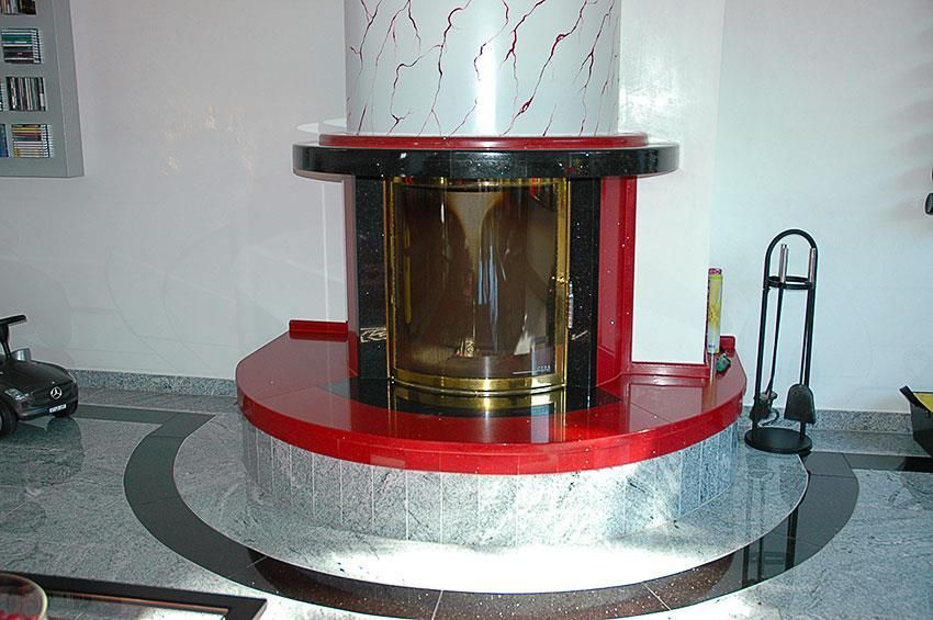 Ein rot-schwarzer Kamin mit einer goldenen Tür