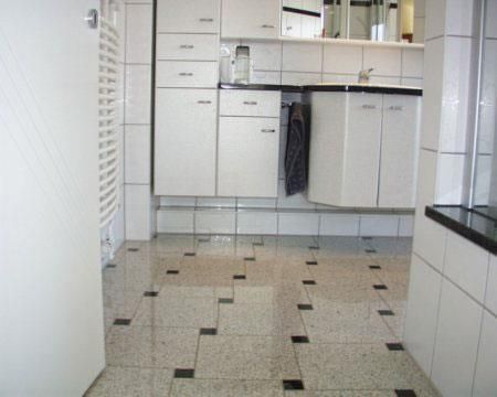 Ein Badezimmer mit weißen Schränken und schwarzen Fliesen