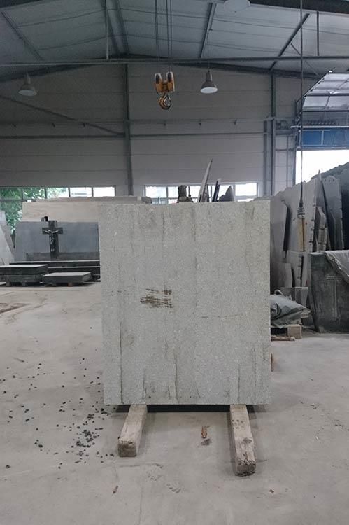 Ein großer Betonblock liegt auf einer Holzpalette in einer Lagerhalle.