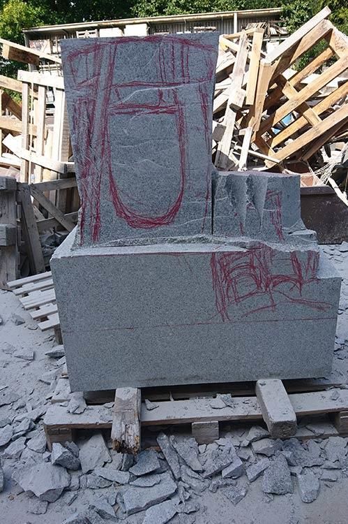 Auf einem Stapel Holzpaletten liegt ein großer Steinbrocken.