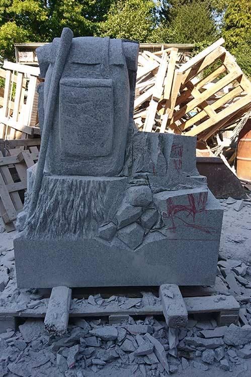 Eine Rucksackstatue sitzt auf einem Steinhaufen.