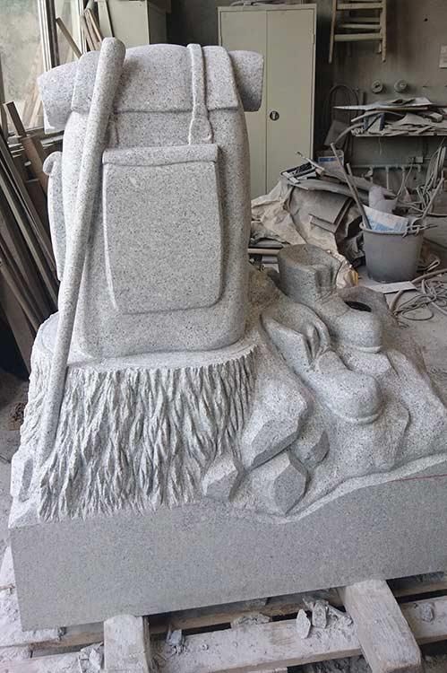 In einer Werkstatt wird eine Statue aus einem Rucksack und einem Stock geschnitzt.