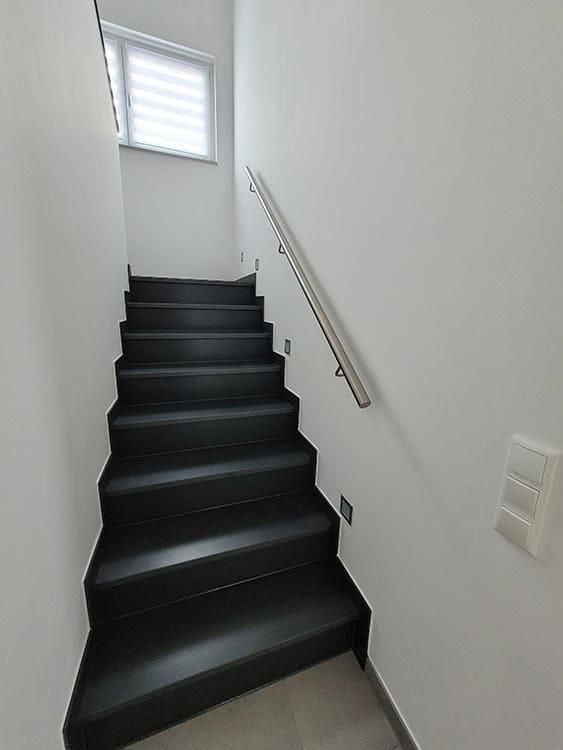 Eine schwarze Treppe führt in den zweiten Stock eines Hauses.