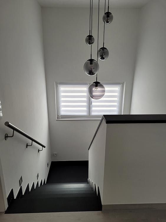 Ein Schwarzweißfoto einer Treppe, die zu einem Fenster hinaufführt.