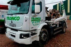 Un camión blanco con la palabra trainco escrita en el costado está estacionado en un lote de grava.