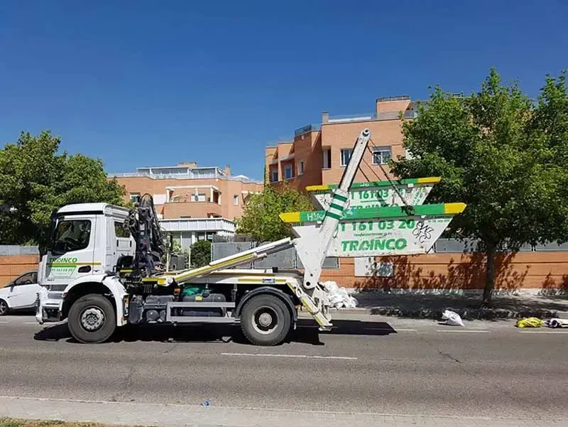 Un camión volquete está estacionado al costado de la carretera frente a un edificio.