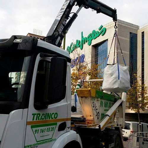 Un camión con una grúa acoplada transporta una bolsa grande.