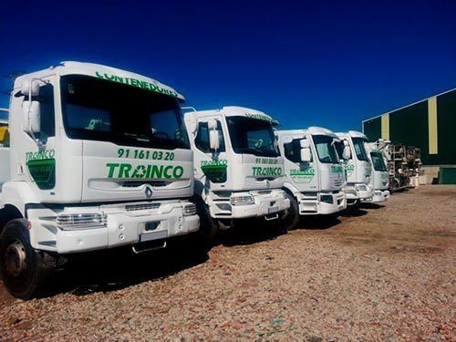 Una fila de camiones de Trainco están estacionados en un estacionamiento de grava.