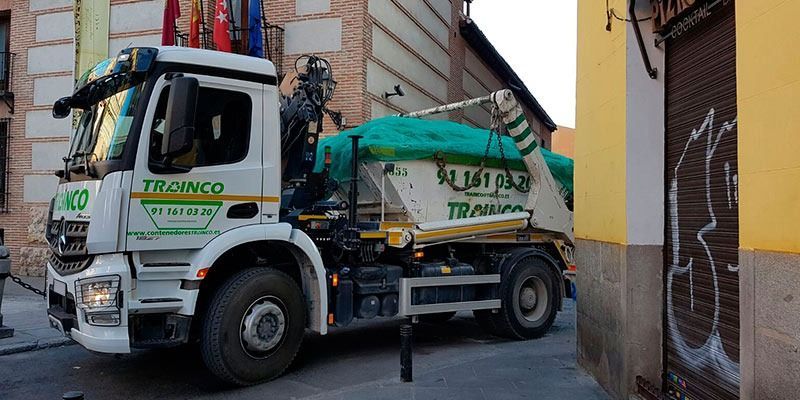 Un camión volquete está estacionado al costado de la carretera frente a un edificio.
