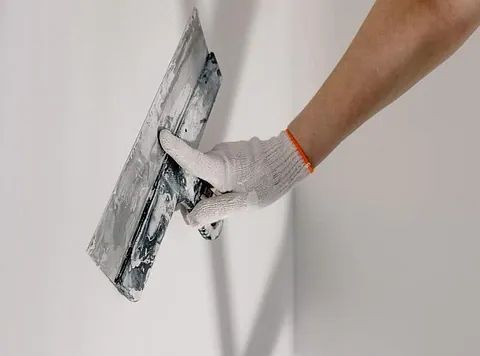 Una persona está enyesando una pared con una paleta.