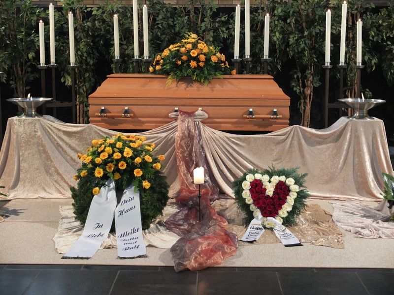 Ein Sarg steht auf einem Tisch mit Blumen und Kerzen