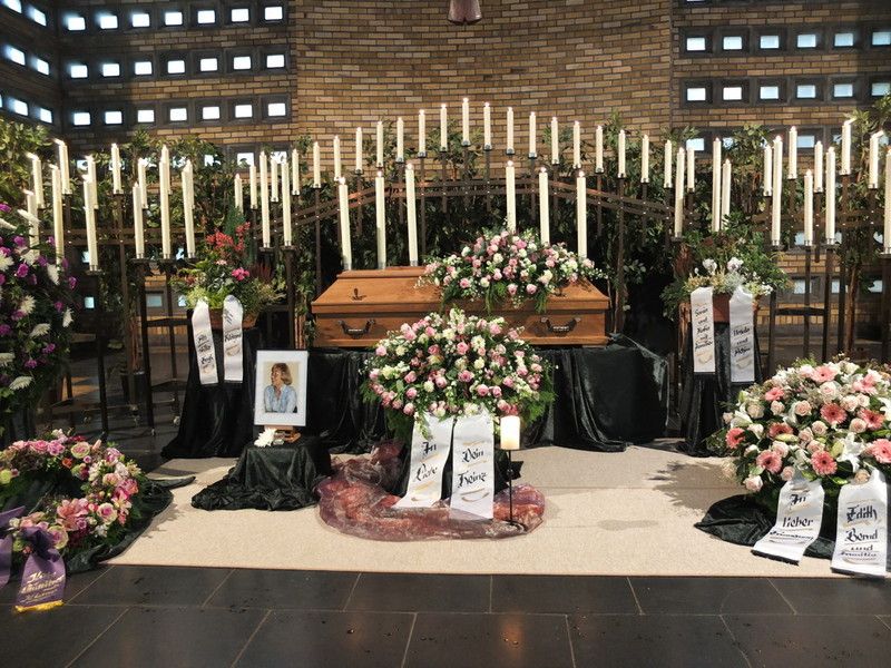 Ein Sarg ist in einer Kirche von Blumen und Kerzen umgeben