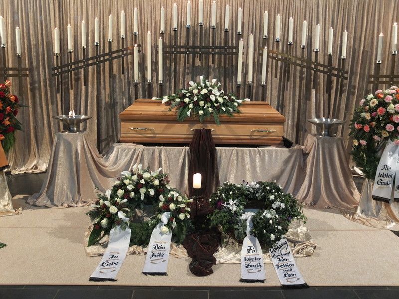 Ein Sarg ist in einer Kirche von Blumen und Kerzen umgeben