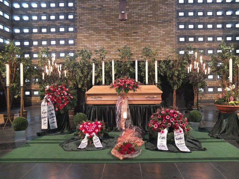 Ein Sarg ist in einer Kirche von Blumen und Kerzen umgeben