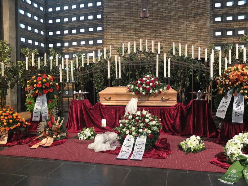 Ein Sarg ist in einer Kirche von Blumen und Kerzen umgeben