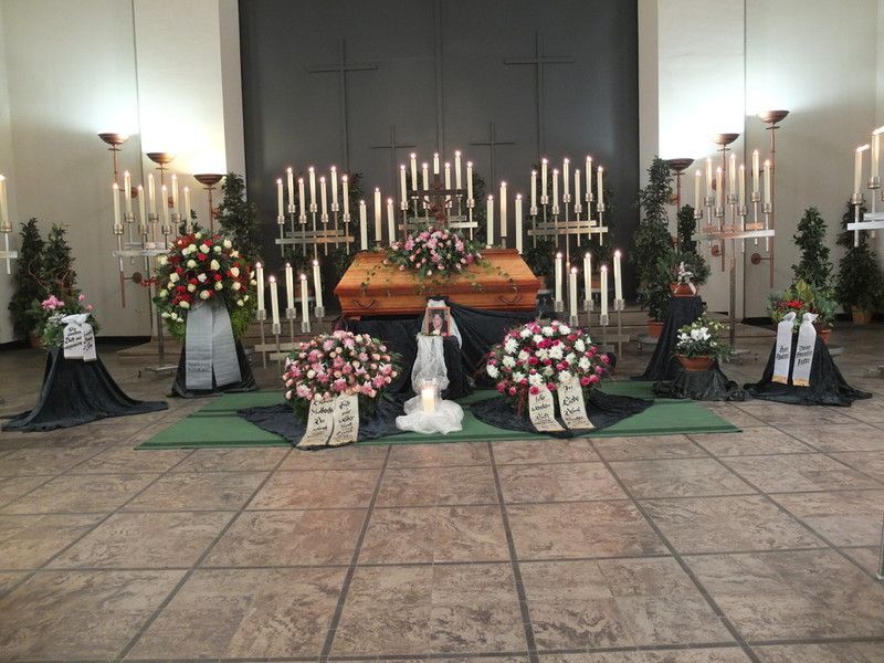 Ein Sarg ist in einer Kirche von Blumen und Kerzen umgeben