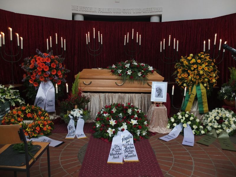 Ein Sarg ist in einer Kirche von Blumen und Kerzen umgeben