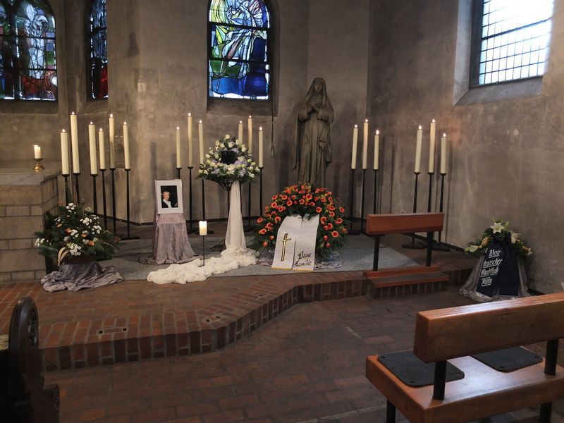 Eine Kirche mit Kerzen, Blumen und einem Bild einer Frau