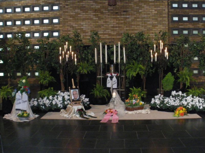 Eine Ausstellung von Blumen und Kerzen vor einer Backsteinmauer