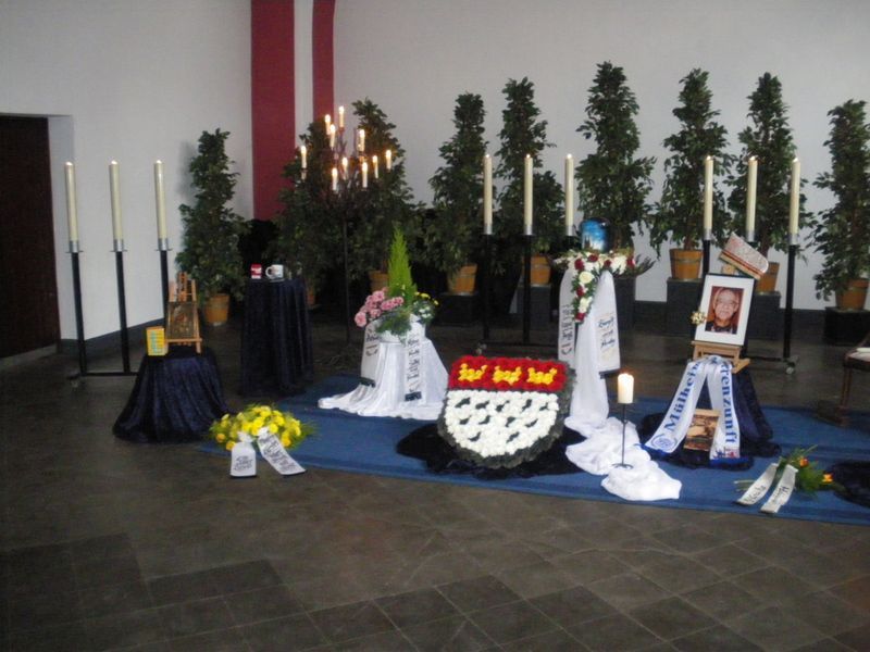 Ein Raum mit Blumen und Kerzen und einem Bild einer Person