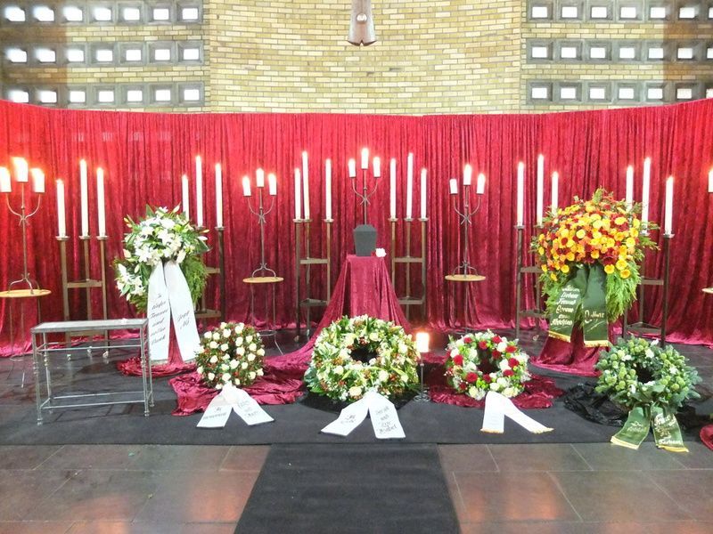 Eine Ausstellung von Blumen und Kerzen vor einem roten Vorhang