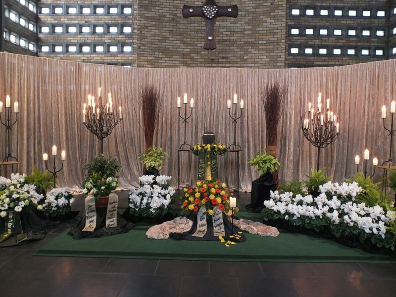 Eine Kirche mit Blumen und Kerzen und einem Kreuz an der Wand