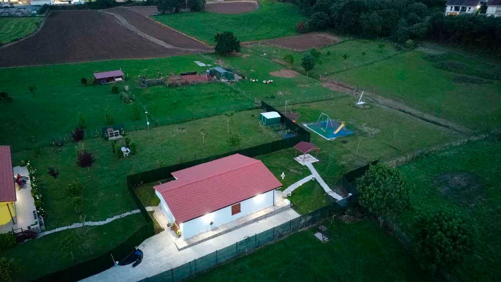 Una vista aérea de una casa con techo rojo en medio de un campo.