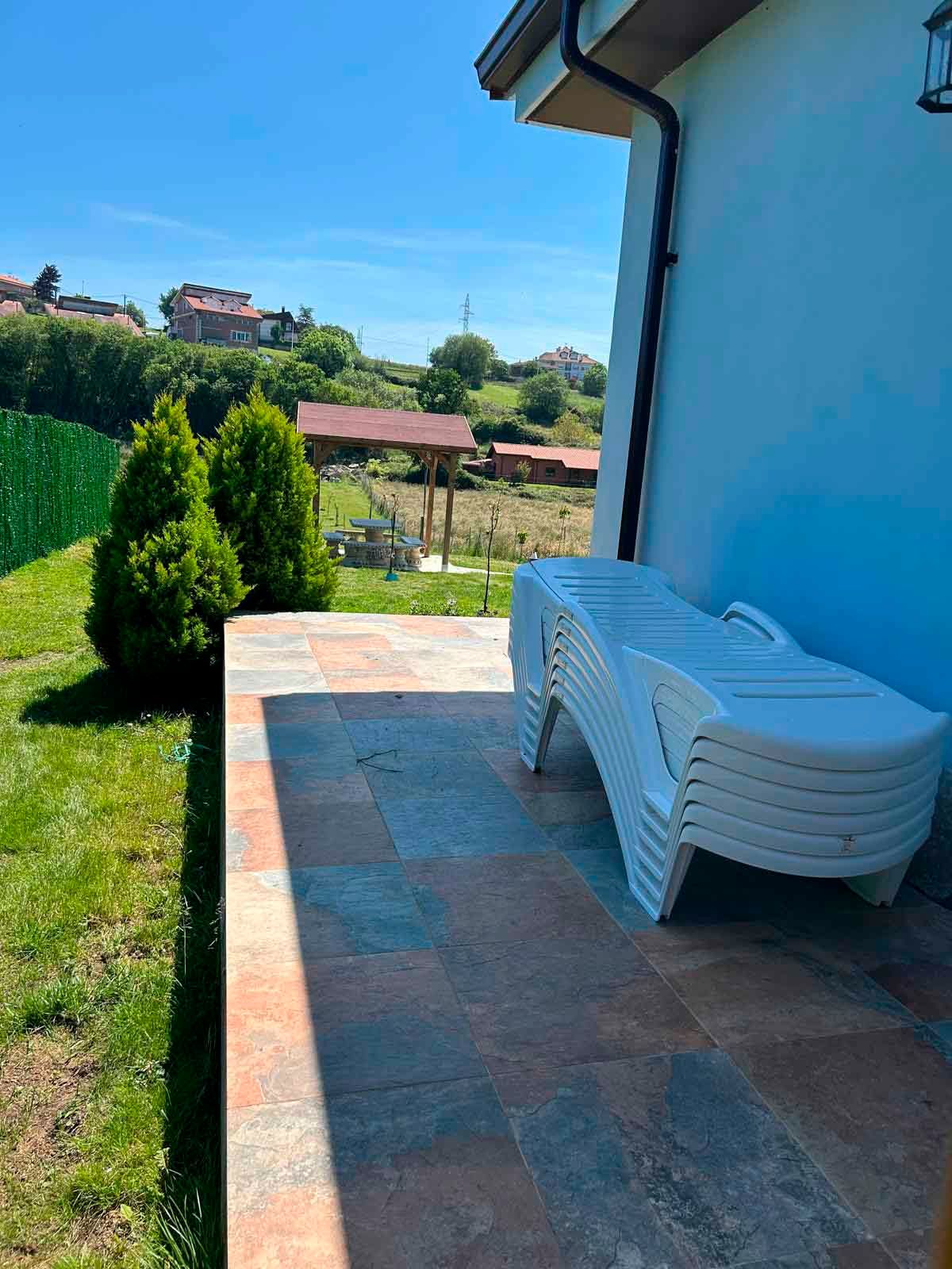 Un patio con una pila de sillas blancas frente a una casa.