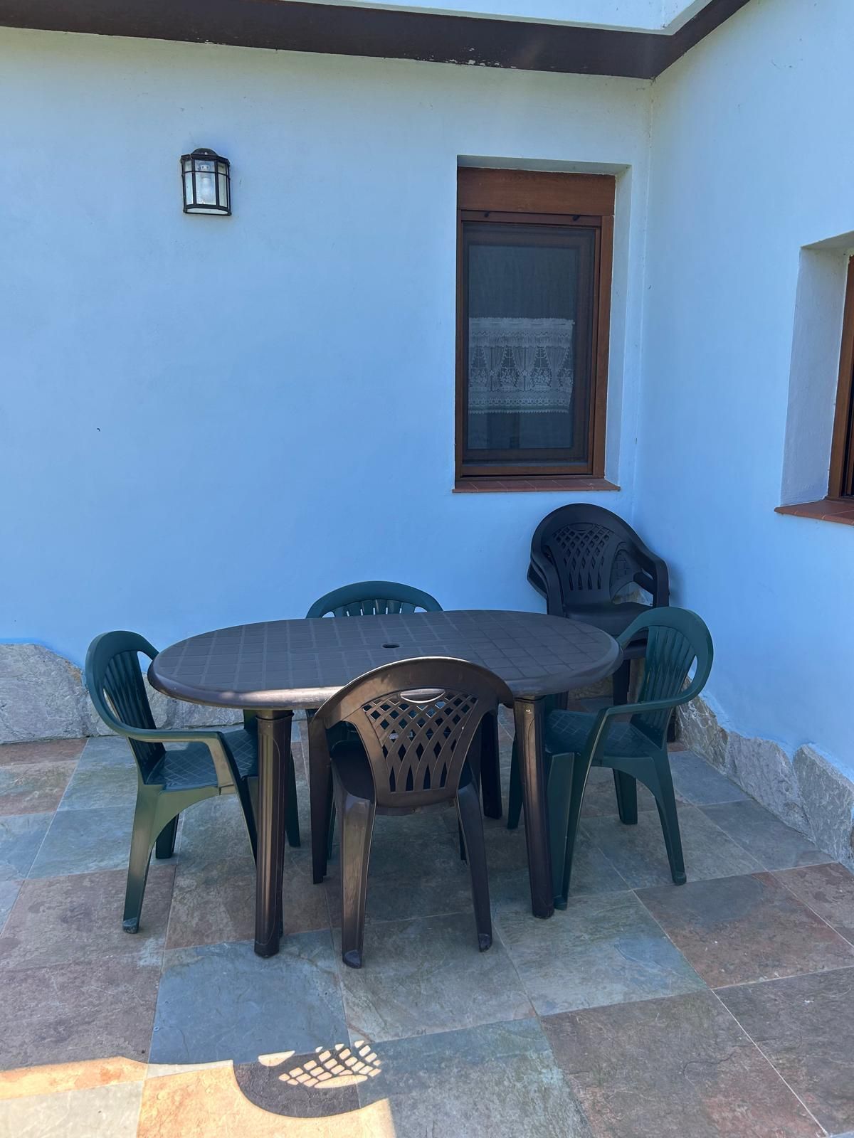 Un patio con una mesa y sillas frente a un edificio blanco.